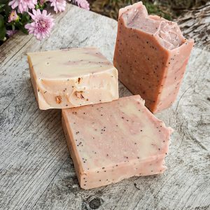 Prairie Rose Farmstead goat milk soap Barbwire & Roses sitting on a wooden surface beside a mum